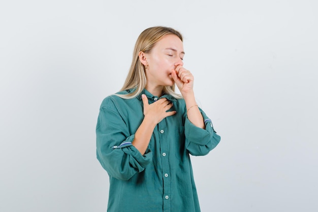 Giovane donna in camicia verde che soffre di tosse e sembra malata
