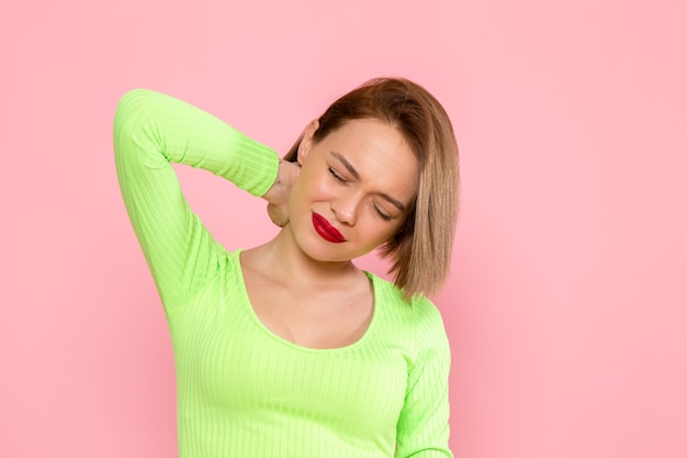 giovane donna in camicia verde e gonna grigia che ha dolore al collo