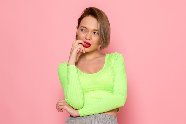 giovane donna in camicia verde e gonna grigia in posa con espressione di pensiero