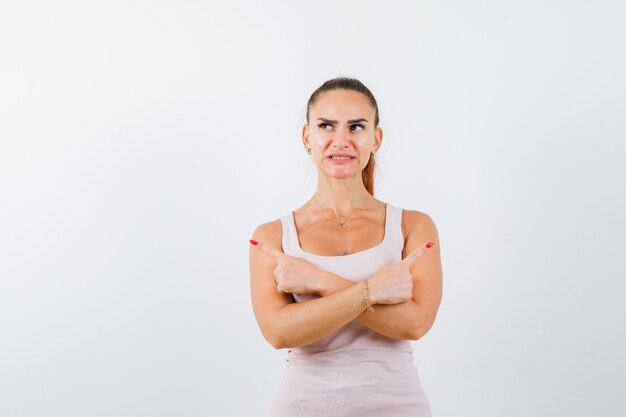 Giovane donna in canottiera che punta da parte e sembra a disagio, vista frontale.