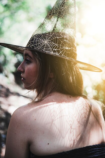 Giovane donna in cappello del mago nella foresta