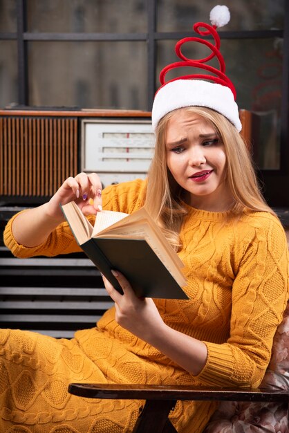 Giovane donna in cappello della Santa che legge un libro.