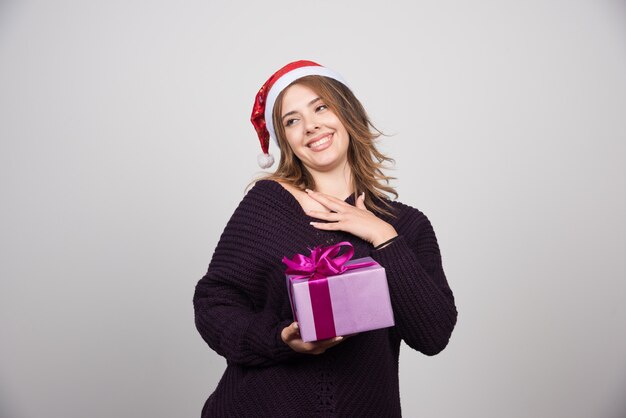 Giovane donna in cappello della Santa che tiene un presente del contenitore di regalo.