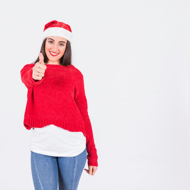 Giovane donna in cappello di Natale con il pollice in su