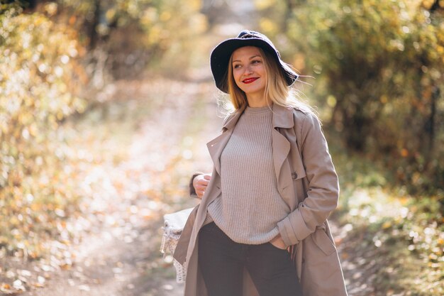 Giovane donna in cappello in un parco in autunno