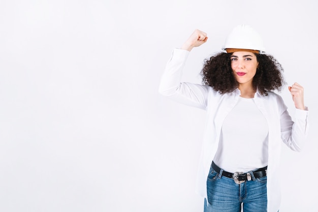 Giovane donna in casco che mostra i muscoli