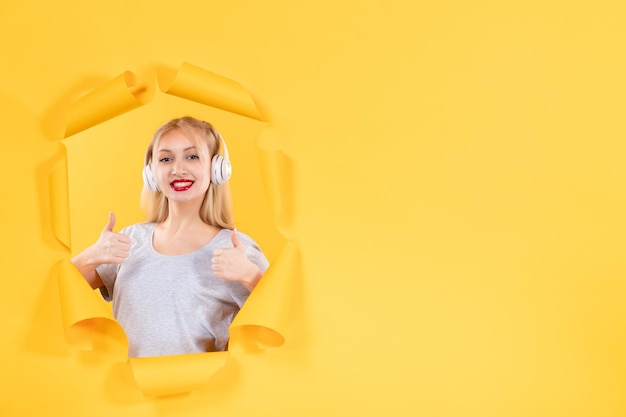 Giovane donna in cuffia su carta gialla strappata surface
