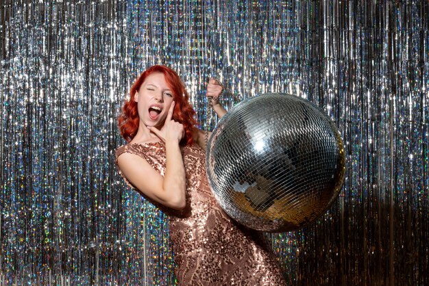 giovane donna in festa con palla da discoteca su tende luminose