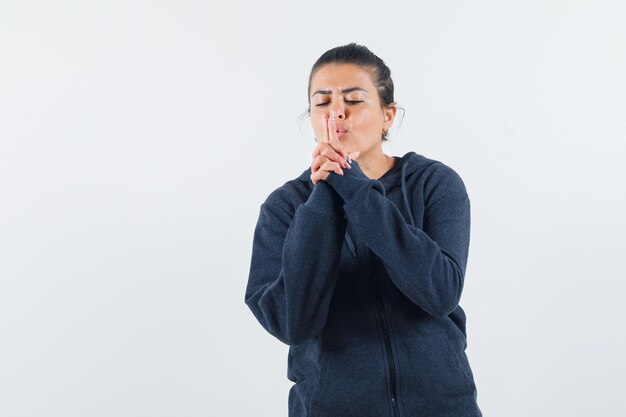 Giovane donna in giacca che soffia alla sua pistola e guardando concentrato