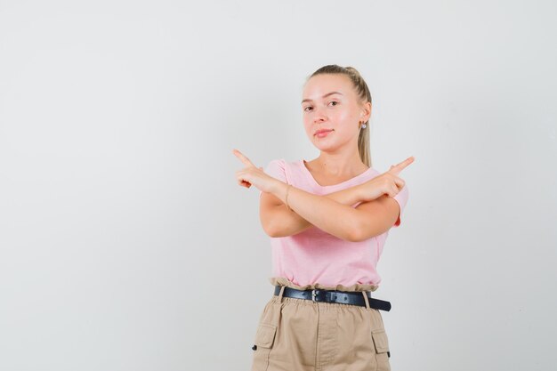 Giovane donna in maglietta e pantaloni che punta lontano e sembra sicura