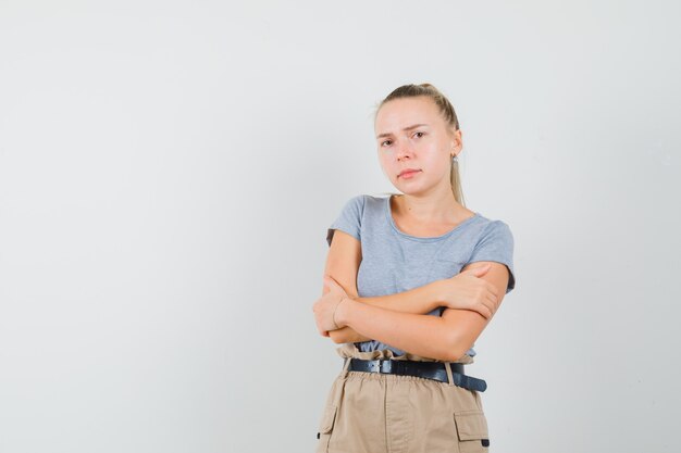 Giovane donna in maglietta e pantaloni che sente freddo e si abbraccia