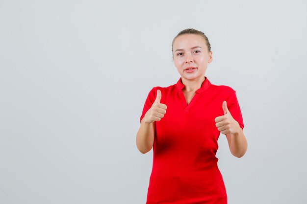 Giovane donna in maglietta rossa che mostra i pollici in su e che sembra soddisfatta