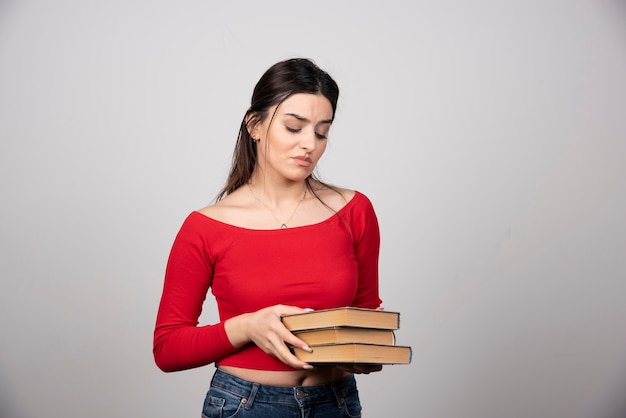 giovane donna in maglietta rossa guardando una copertina di un libro.