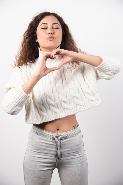 Giovane donna in maglione bianco con capelli ricci in posa. Foto di alta qualità