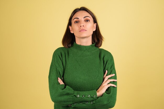 Giovane donna in maglione caldo verde con le braccia incrociate