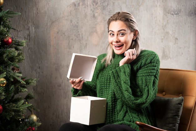 Giovane donna in maglione caldo verde entusiasta di un regalo