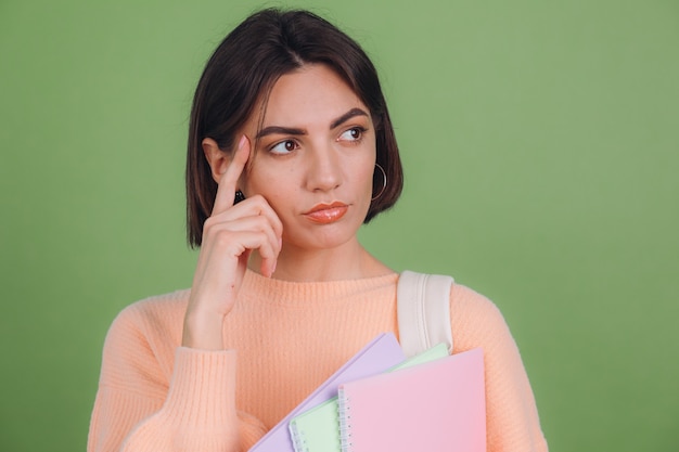 Giovane donna in maglione pesca casual isolato sulla parete di colore verde oliva