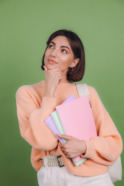 Giovane donna in maglione pesca casual isolato sulla parete di colore verde oliva