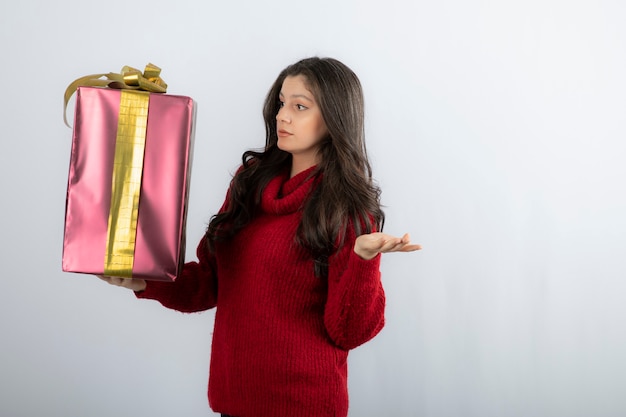 Giovane donna in maglione rosso guardando i regali di Natale.