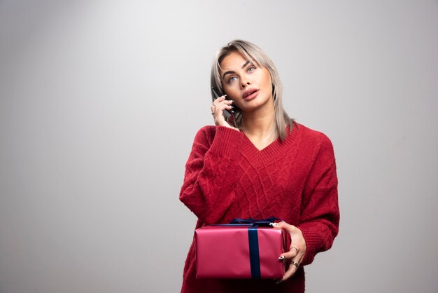 Giovane donna in maglione rosso parlando al cellulare.