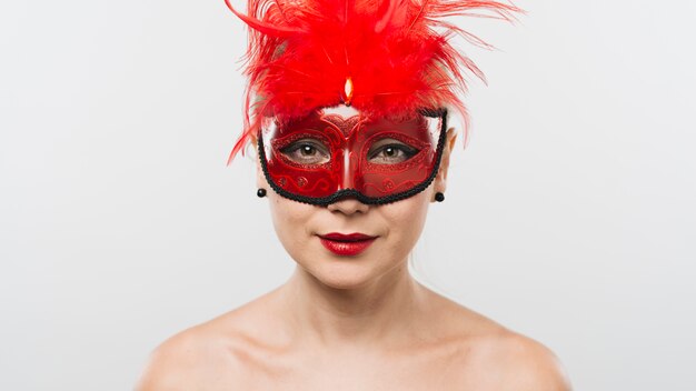 Giovane donna in maschera con piume rosse