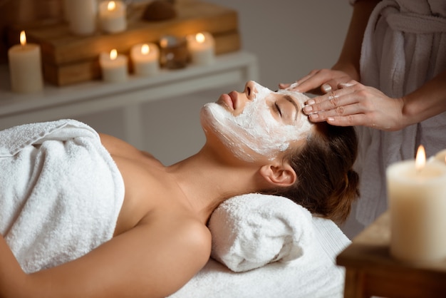 Giovane donna in maschera per viso rilassante nel salone spa.