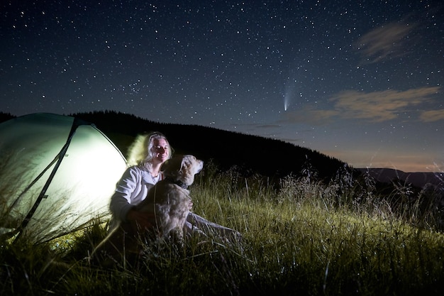 Giovane donna in montagna che osserva la bella notte stellata e una cometa