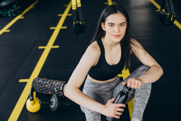 Giovane donna in palestra, bevendo acqua