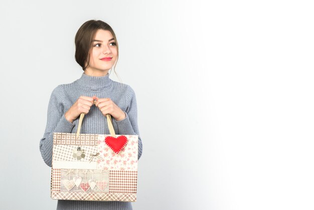 Giovane donna in piedi con la borsa regalo