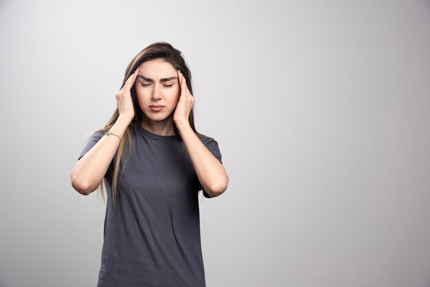 Giovane donna in piedi e tocca la testa per il dolore