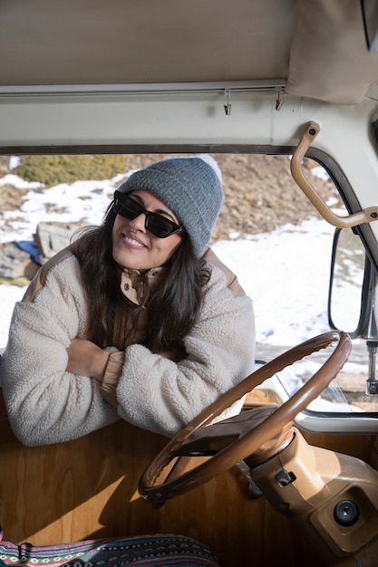 Giovane donna in piedi fuori dal camper durante il viaggio invernale