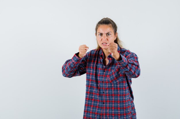 Giovane donna in piedi in boxer posa in camicia controllata e guardando fiducioso