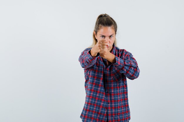 Giovane donna in piedi in boxer posa in camicia controllata e guardando fiducioso