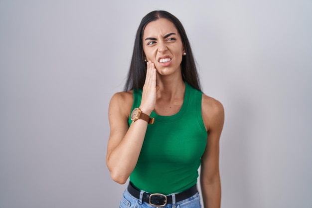 Giovane donna in piedi su sfondo isolato toccando la bocca con la mano con espressione dolorosa a causa di mal di denti o malattia dentale sui denti. dentista