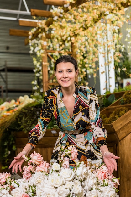 Giovane donna in piedi vicino a fiori di rosa