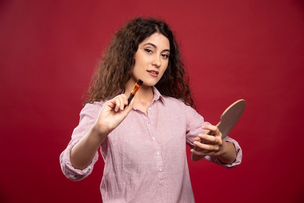 Giovane donna in posa con pennello e tavolozza di vernice.