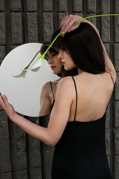 Giovane donna in posa con specchio e fiore