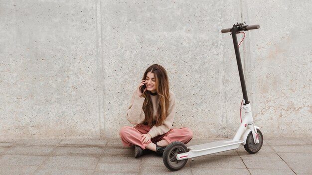 Giovane donna in posa con uno scooter elettrico