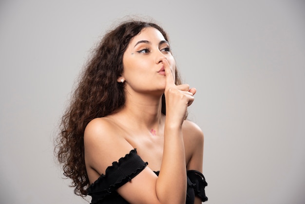 Giovane donna in posa in camicetta nera con capelli ricci. Foto di alta qualità