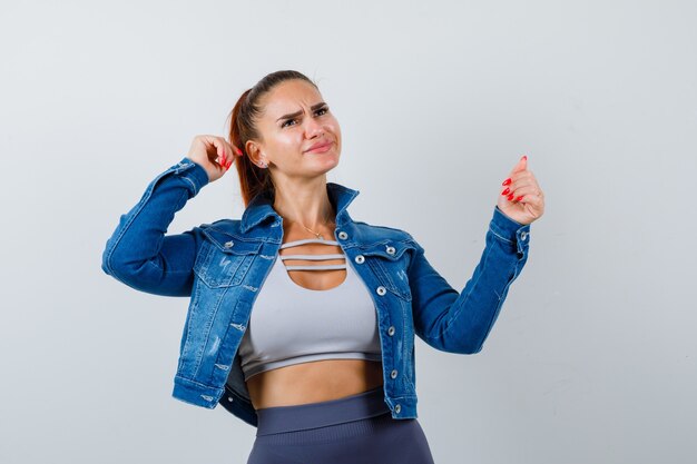 Giovane donna in posa mentre distoglie lo sguardo in alto, giacca di jeans e sembra ansiosa. vista frontale.