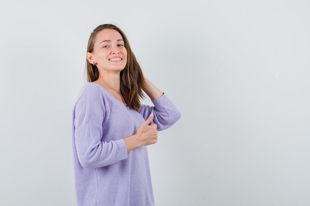 Giovane donna in posa mentre in piedi in camicia casual e sembra felice. vista frontale.