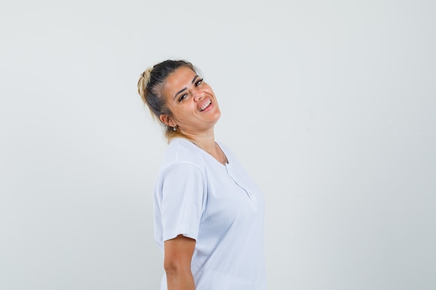 Giovane donna in posa mentre in piedi in t-shirt e sembra sicura