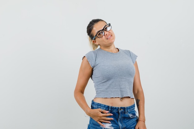 Giovane donna in posa mentre in piedi in t-shirt, pantaloncini e sembra affascinante