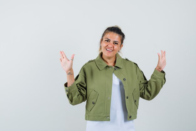 Giovane donna in posa mentre mostra le palme in giacca di t-shirt e sembra allegra