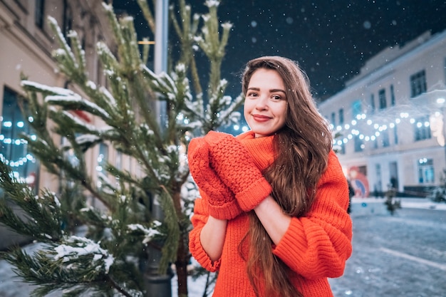 Giovane donna in posa vicino all'albero di Natale sulla strada