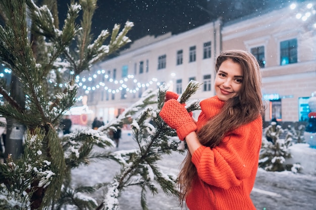 Giovane donna in posa vicino all'albero di Natale sulla strada