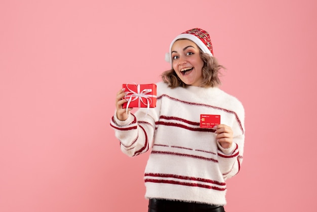 giovane donna in possesso di Natale presente e carta di credito in rosa