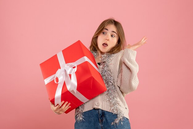 giovane donna in possesso di Natale presente nelle sue mani sul rosa