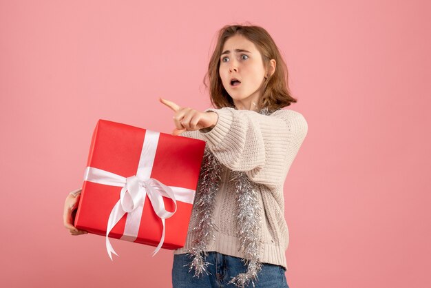 giovane donna in possesso di Natale presente nelle sue mani sul rosa