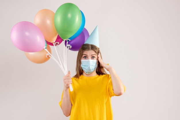 giovane donna in possesso di palloncini colorati in maschera sterile su bianco